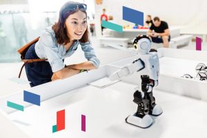 Woman interacting with a small robot in a tech setting.