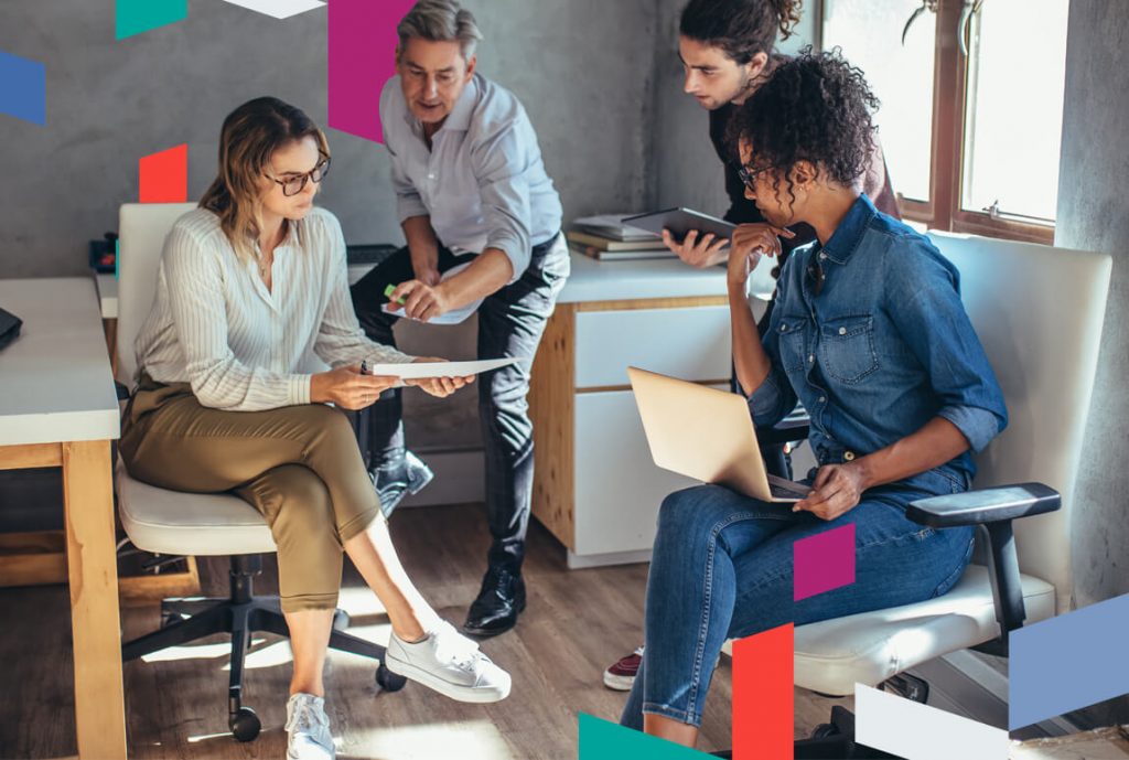 Four people in a modern office setting discussing business documents.