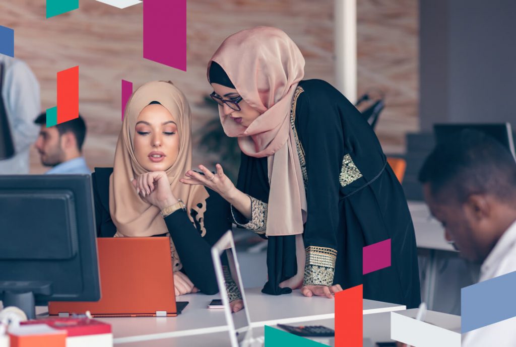 Women in hijabs discussing in an office with SPC Free Zone branding.