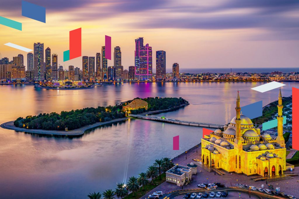 Skyline of Sharjah with illuminated mosque and cityscape at dusk.