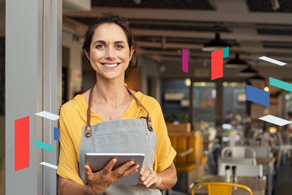 Smiling woman with a tablet in a café with SPC Free Zone graphics.