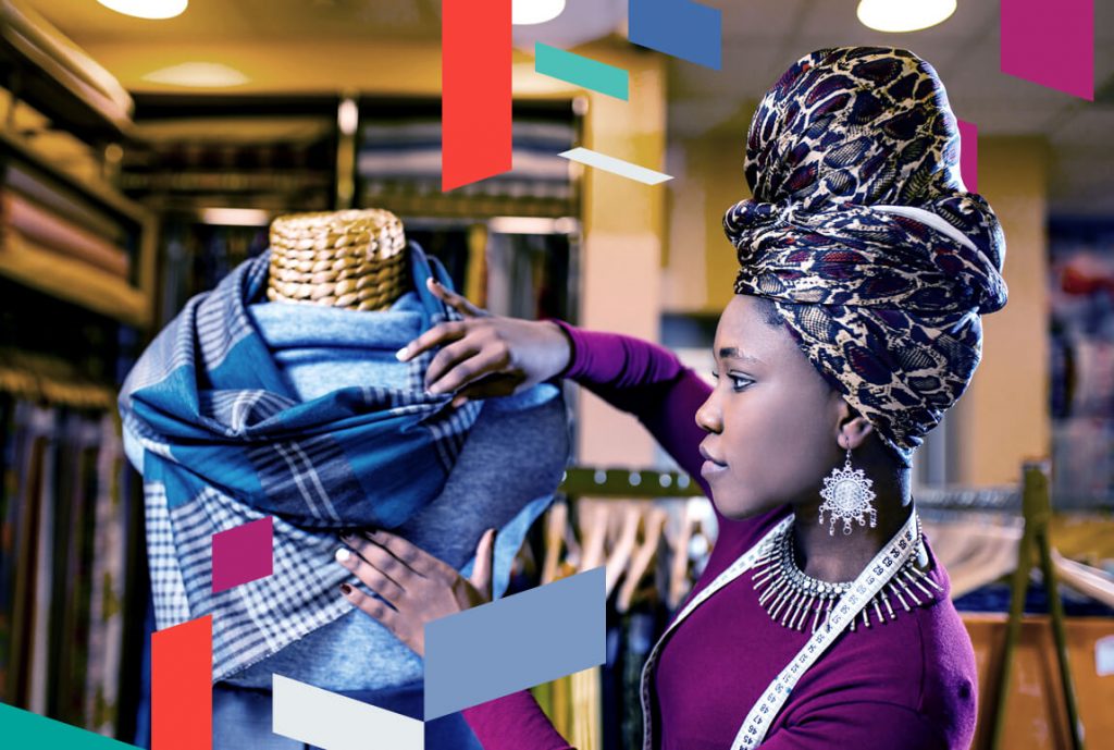 Person adjusting fabric on a mannequin in a textile store, colorful design elements overlay.