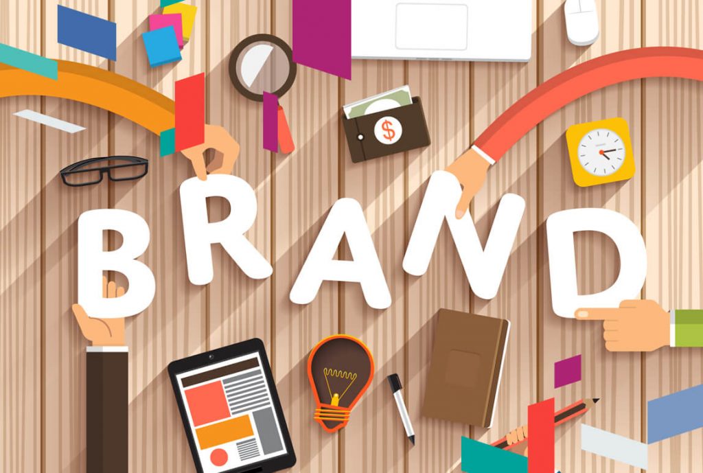 Illustration of hands holding letters spelling 'BRAND' with business-related items around.