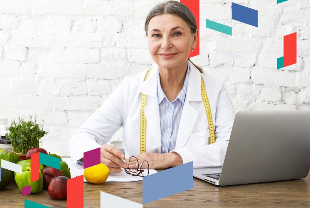 Woman in office with laptop, fruits, and vegetables, suggesting health and business synergy.