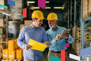 Two men in hard hats discussing in a warehouse with colorful shapes around them.