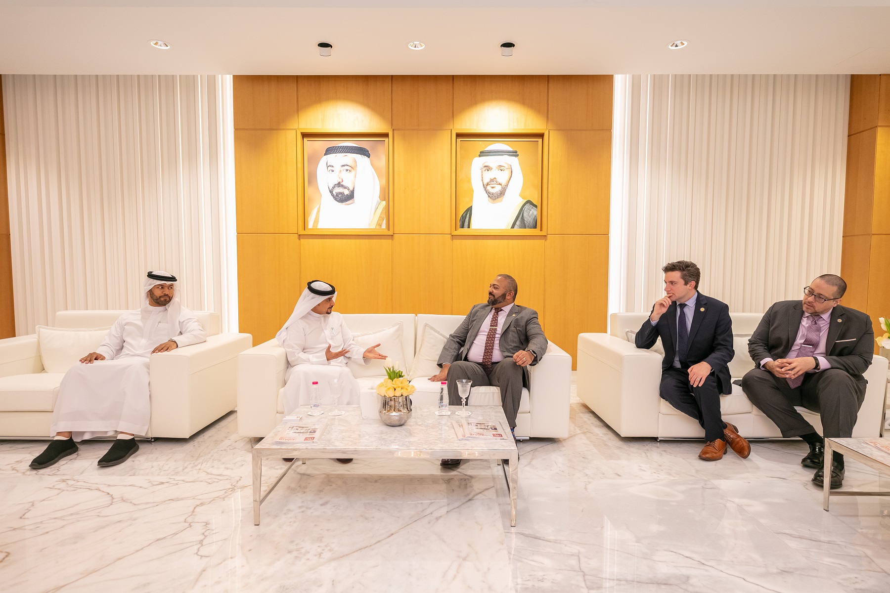 Meeting in a UAE business office with five men seated, discussing free zone companies.