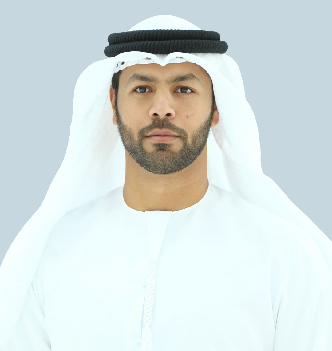 Man in traditional attire on light blue background.