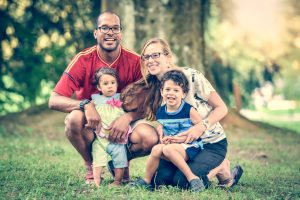 Family sitting on grass in a park.