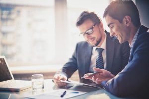 Two businessmen discussing documents in a bright office.