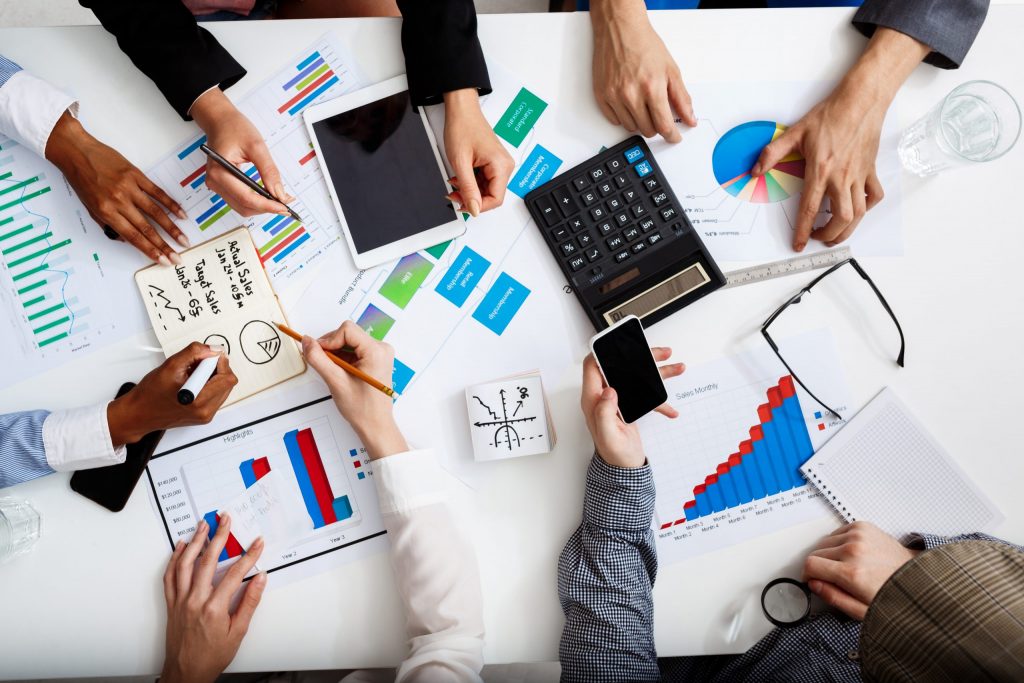 Team discussing business setup with charts and technology devices on a table.