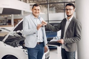 Two men exchanging car keys in a dealership.