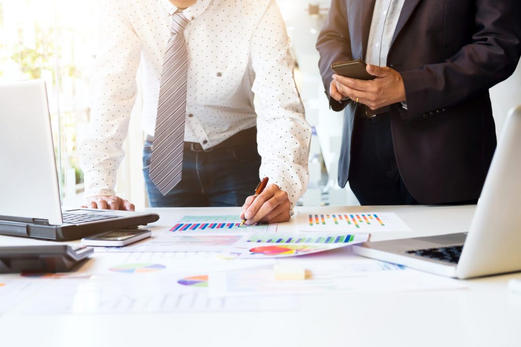 People discussing business setup with charts and laptops in an office.