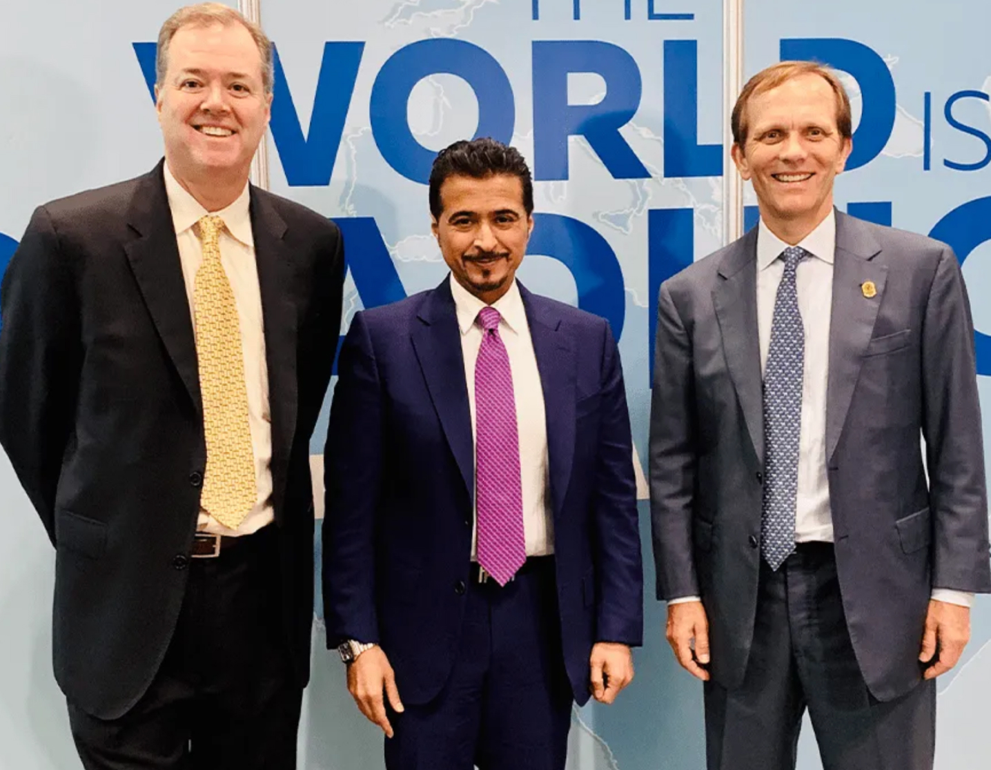 Three men in business attire at an event.