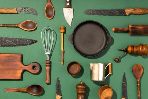 Various kitchen utensils arranged on a green background.