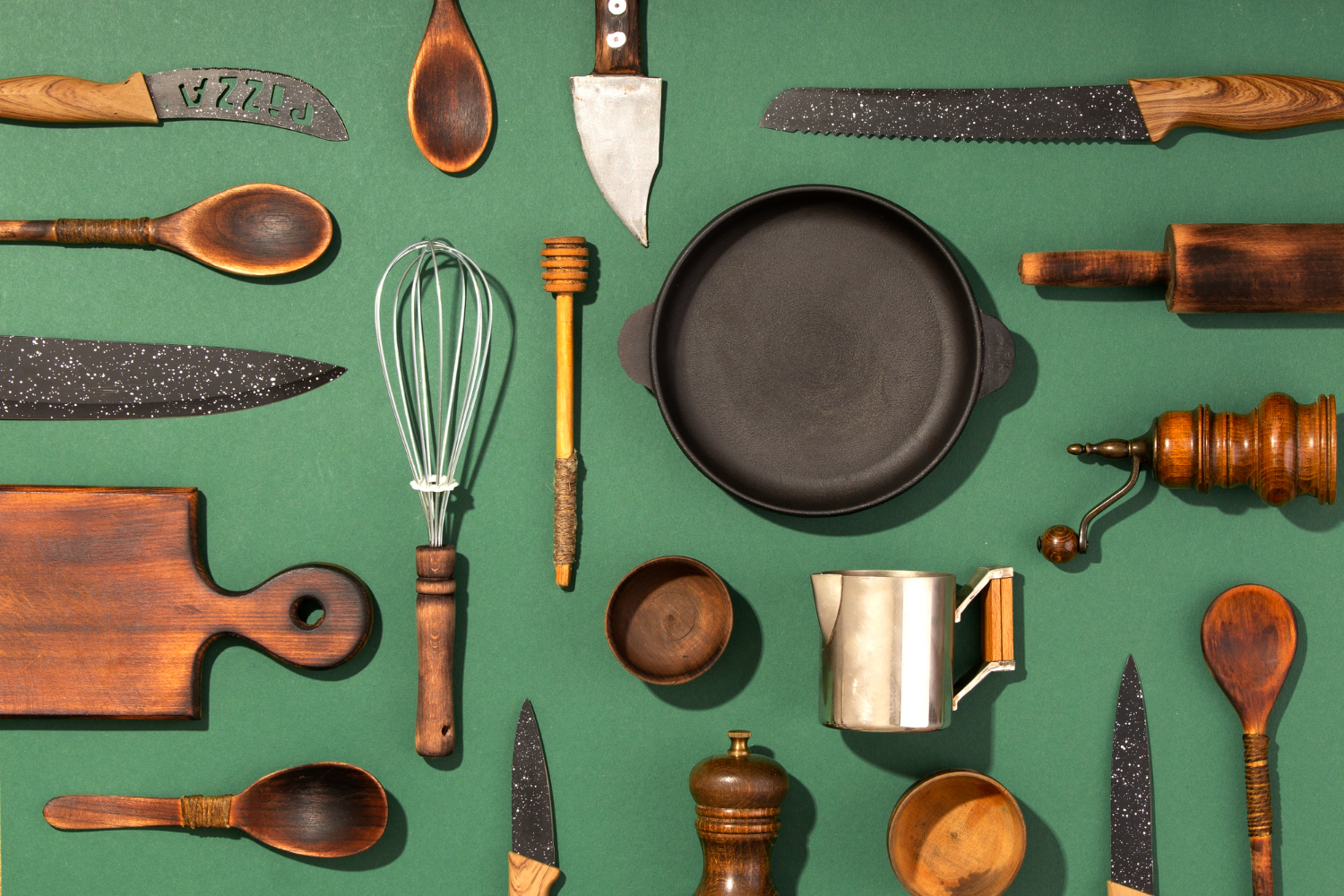 Various kitchen utensils arranged on a green background.