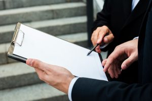 Two professionals reviewing documents on a clipboard.