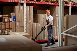 Worker moving boxes in a warehouse with shelving.