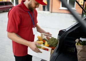 Delivery person loading vegetables into a car.