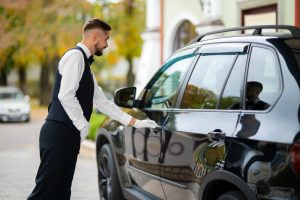 Valet opening a car door outside a building.