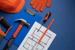 Construction tools and building plans on blue background.