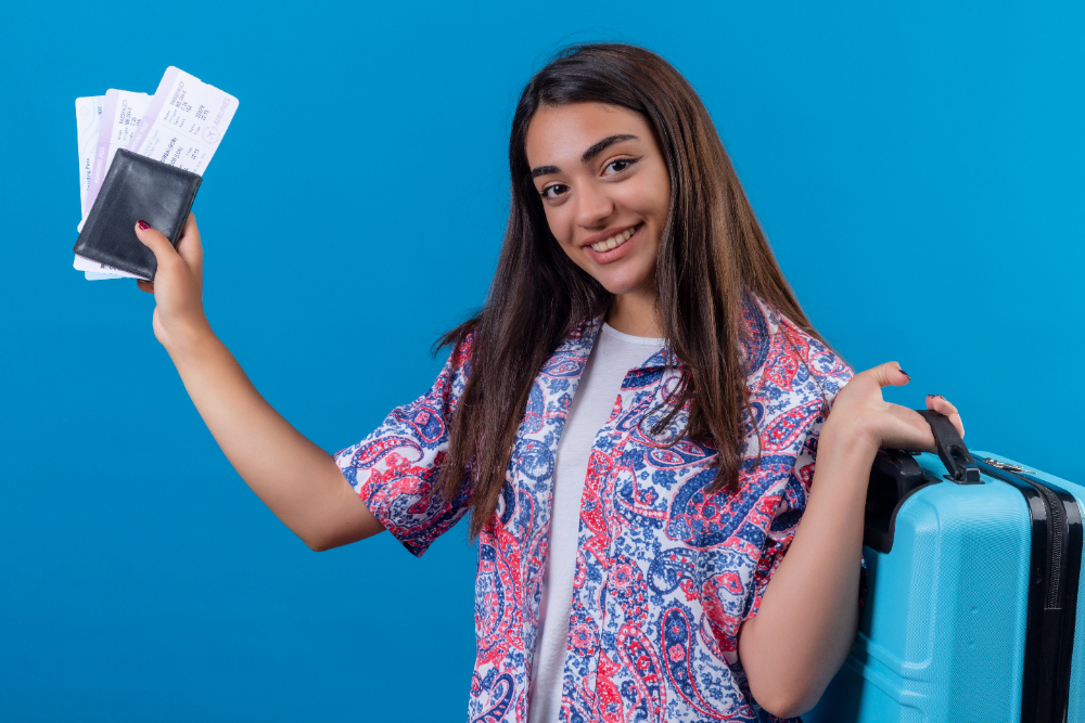 Smiling woman holding travel documents and suitcase, ready for business in UAE.